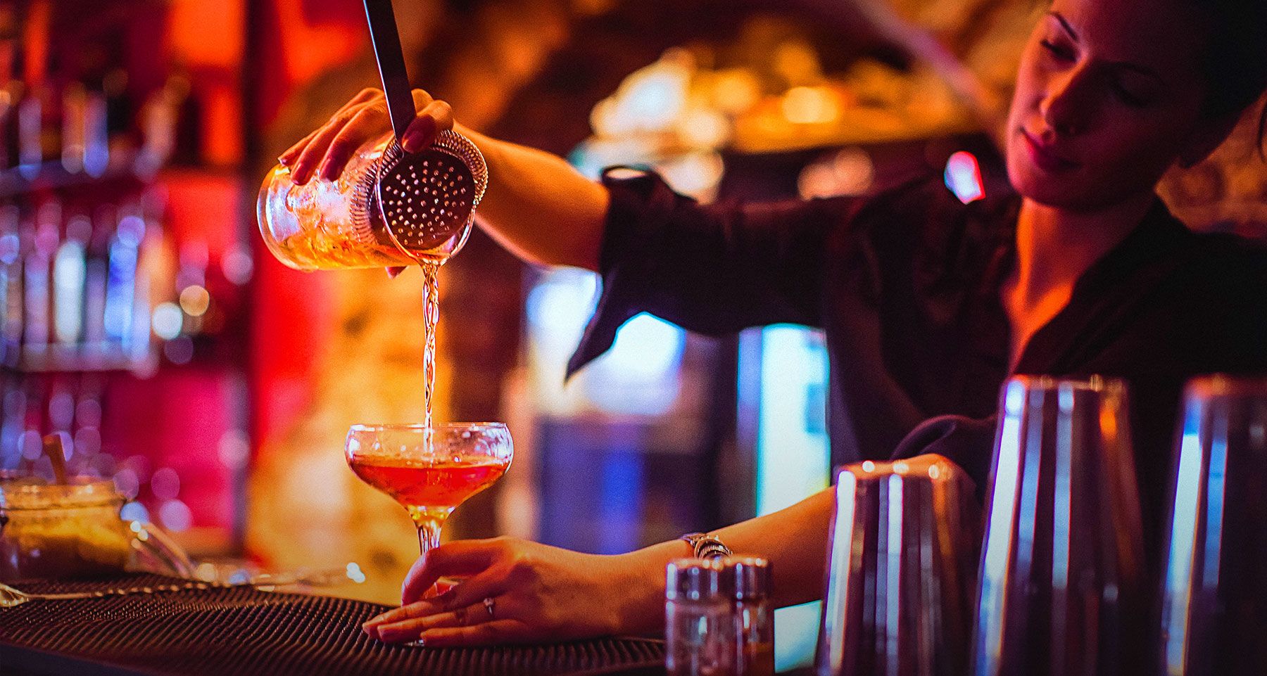a bartending pouring a cocktail
